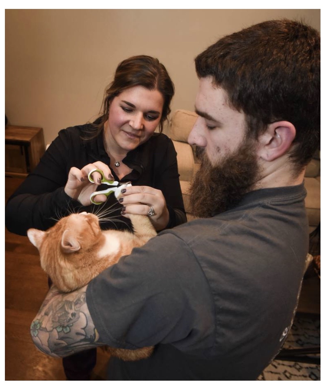 man and a woman trimming a cats nails